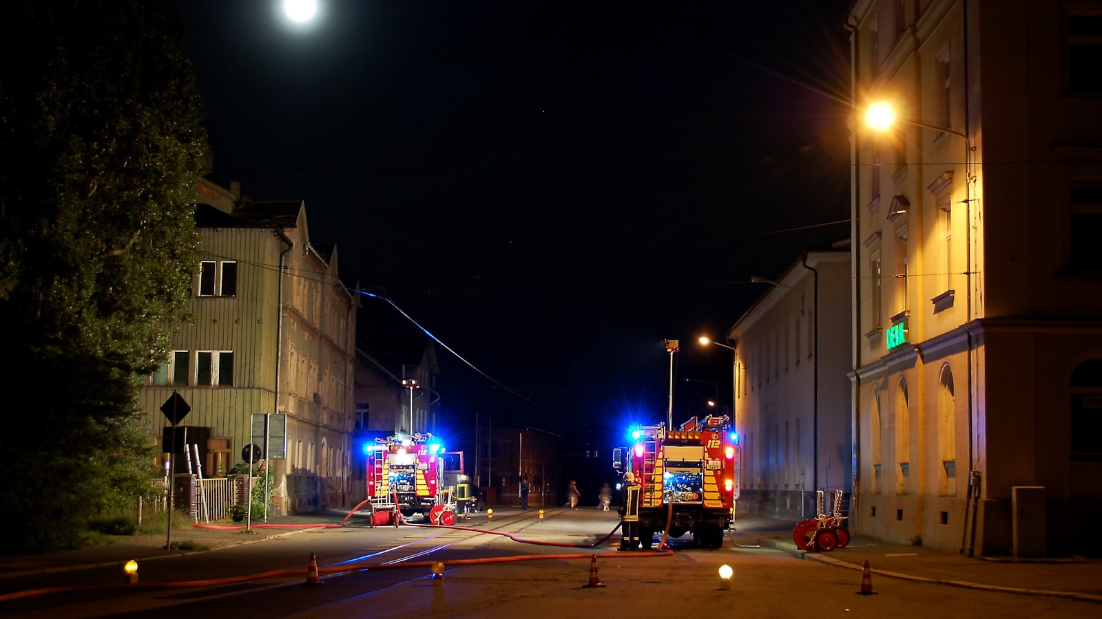 Zwei Feuerwehrfahrzeuge mit Blaulicht bei einem nächtlichen Einsatz auf einer Ortsstraße