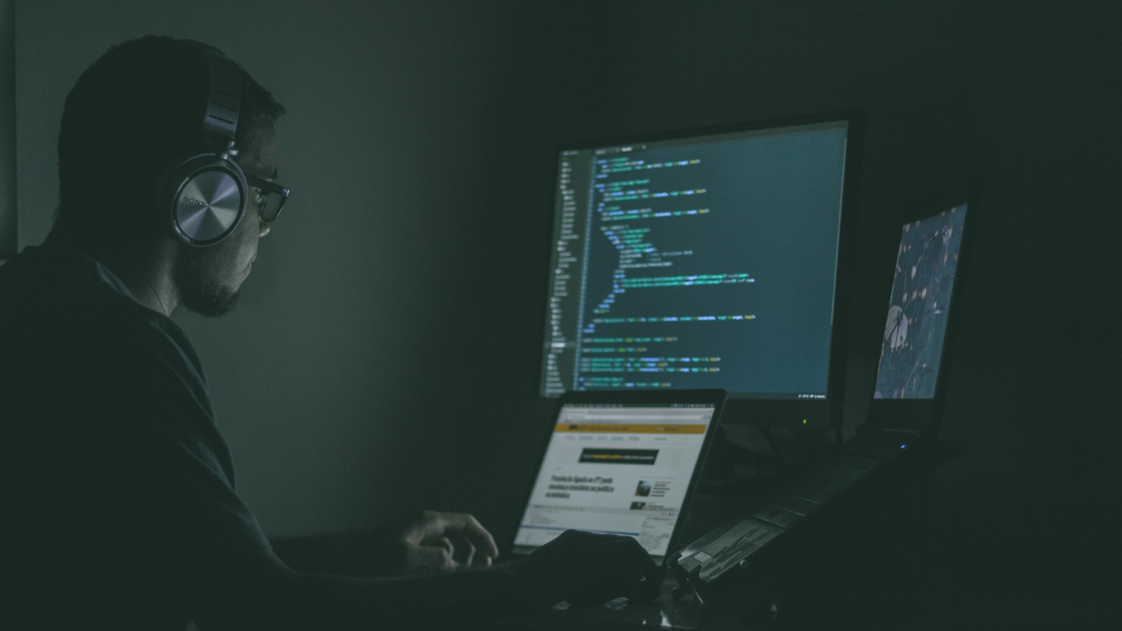 Person arbeitet nachts an mehreren Bildschirmen – Sinnbild für einen Cyberangriff