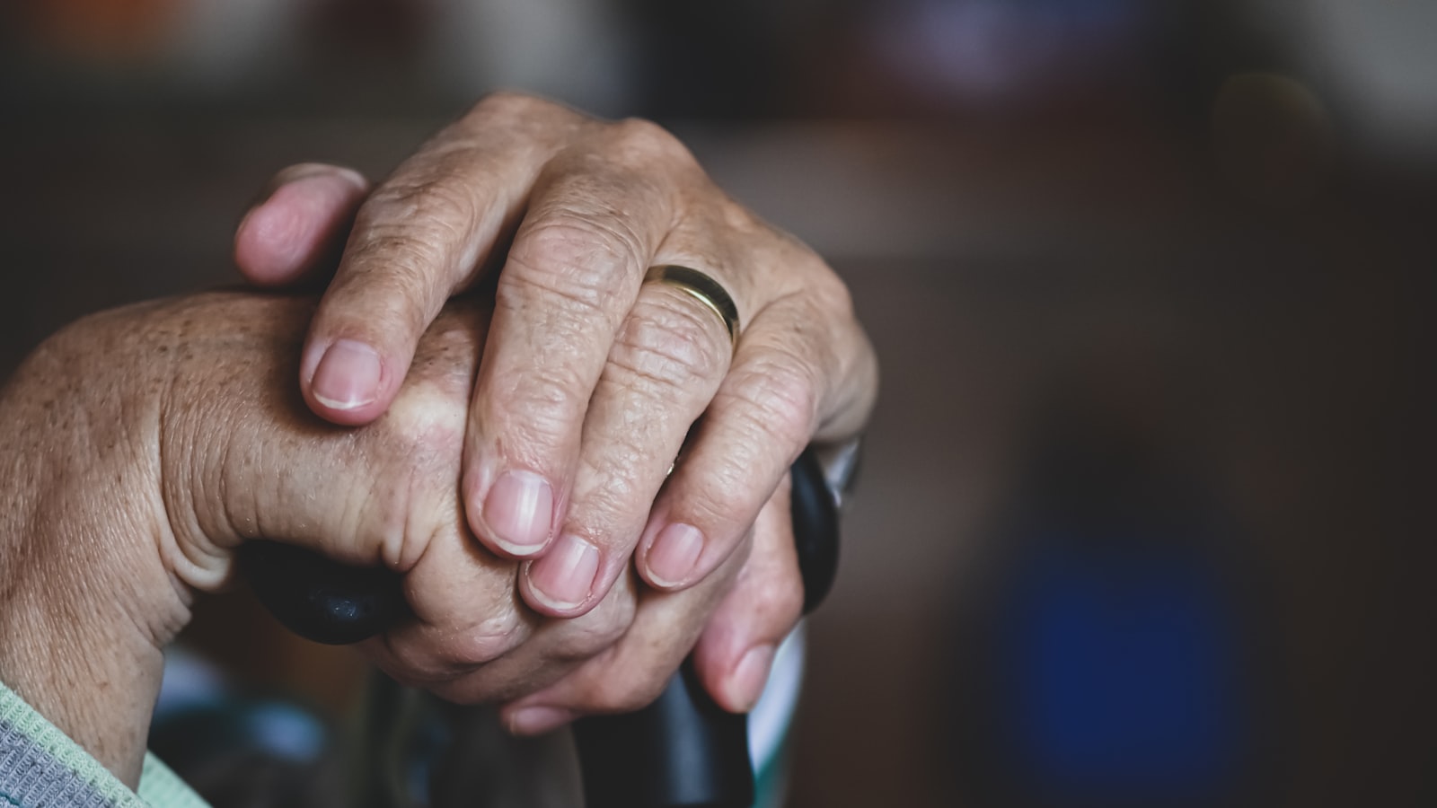 Angehörige hält die Hand einer pflegebedürftigen Person
