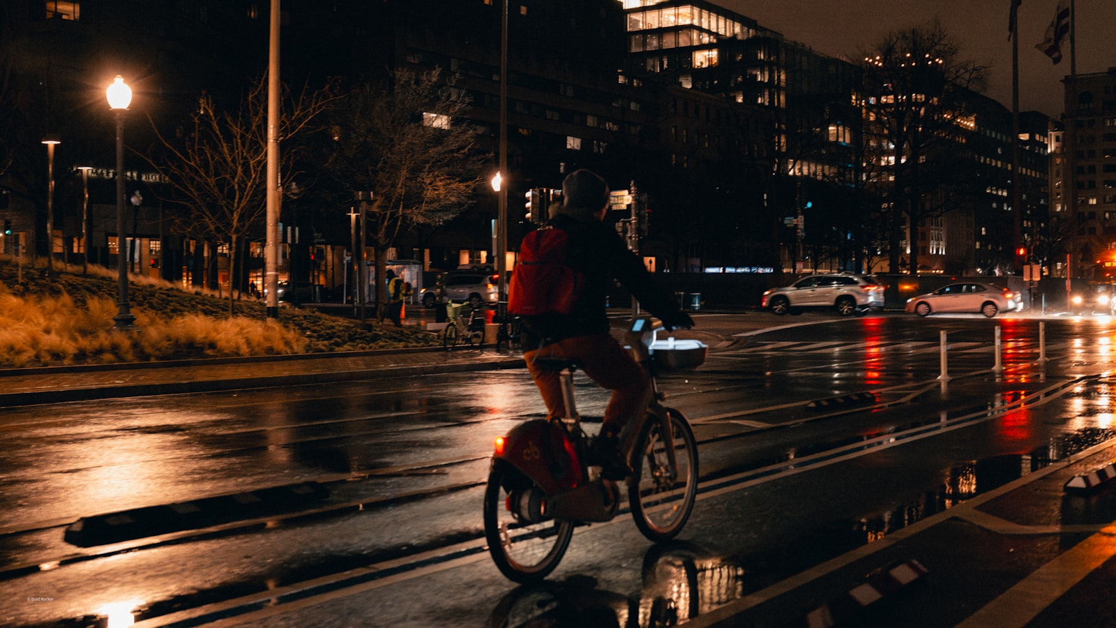 Radfahrer auf einer nassen Straße in der Dämmerung im Stadtverkehr