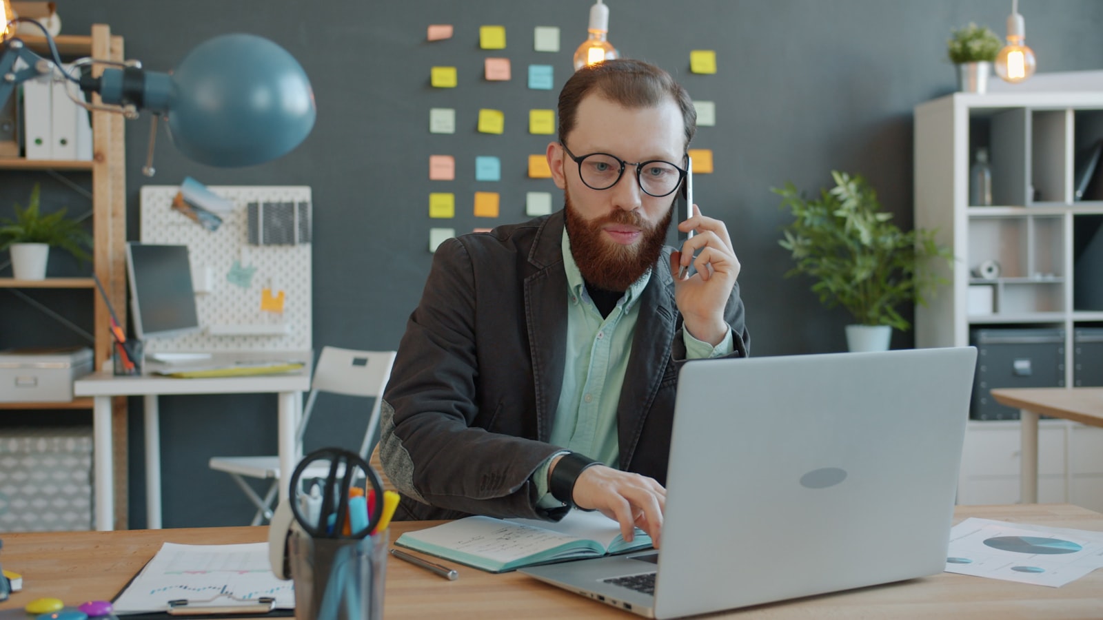 Mitarbeiter telefoniert am Schreibtisch vor dem Laptop im Büro